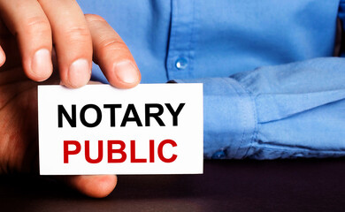 NOTARY PUBLIC is written on a white business card in a man's hand. Advertising concept