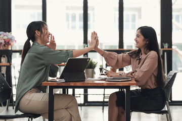Give me five. Two young Asian businesswoman work in a coffee shop enjoying their hands touching. giving high five