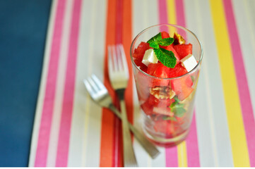 Very refreshing watermelon salad garnished with walnut, feta cheese and mint leaves and served in a glass. Healthy and nutritious fruit snacks and salads.