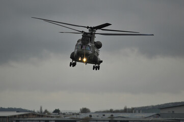 Chinook helicopter landing approach head on view with landing lights on against a dark cloudy sky