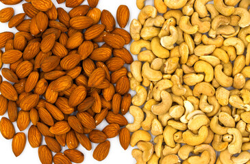 Cashew and almond pile on white background. Natural organic nut kernel. Protein superfood or healthy snack. Nuts pile scattered on white table top view. Granola package design. Healthy eating