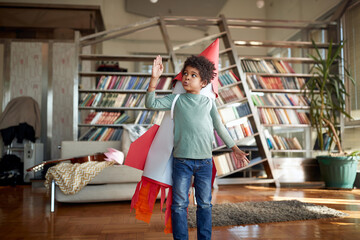 Cute afro american kid playing with paper rocket