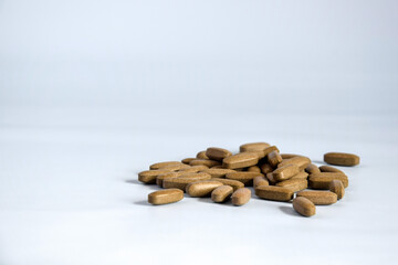 Natural brown pressed medicinal herb, pills on blue background. Alternative medicine concept of...