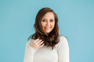 Obraz premium Cute friendly casual woman smiling on blue background, portrait