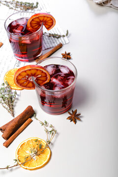 Cold mulled wine with cherry and bloody orange. Alcoholic beverage still life. Sicilian oranges, cinnamon sticks, oregano, anise and dried ginger. Light background. Copy space