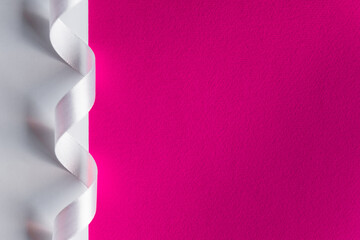 Pink paper background with minimalist ribbon decor. Contrast and minimalism concept.