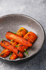 grilled carrot on ceramic plate with microgreen closeup with copyspace on concrete background