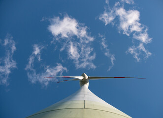 View from beneath the wind turbine directly to the rotor blade. Some clouds framing the rotor...