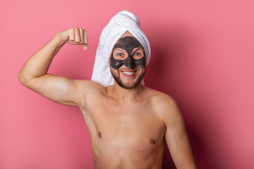 smiling man with a cosmetic mask on his face, naked shows muscles on a pink background