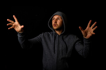 Man in a hood is touching something on a dark background