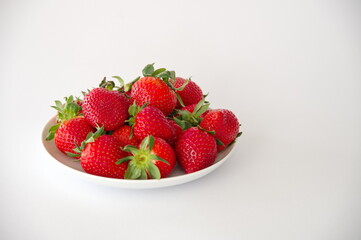 Strawberries on a plate against white background