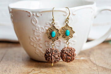 brass turquoise stone Indian seed earrings on white cup background