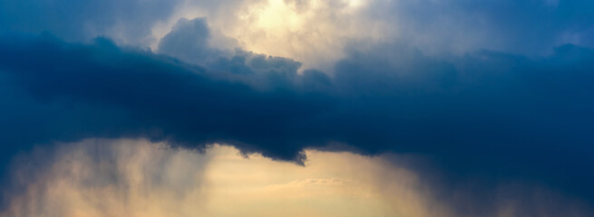 Naklejka na ściany i meble Dark storm clouds in the evening sky at sunset
