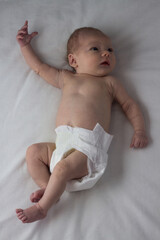 The Little Child in the Diaper, Baby, lies on a white bed. White background