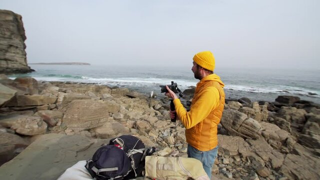 Operator is preparing his camera for taking pictures of beautiful marine landscape. Seaside