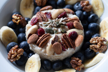 CLOSE UP HEALTHY ORGANIC BREAKFAST PORRIDGE  TOPPED WITH NUTS FRUIT & SEEDS 