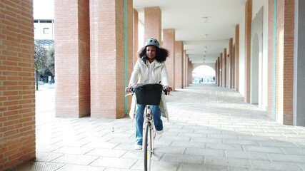 Young commuter woman in city in sustainable way wearing bike helmet with protective face mask against Coronavirus Covid-19 pandemic rides her bicycle on way home to work - Safety and commuting concept - Powered by Adobe