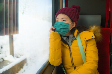 train traveling in times of covid19 - young happy and beautiful Asian Japanese woman in face mask...
