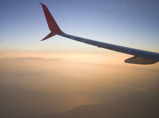 The view from the porthole on the wing of the plane against the background of the rising morning sun.