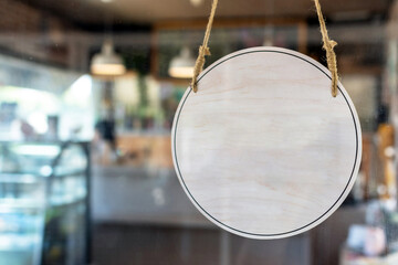 blank vintage wooden sign board hanging on glass door in modern cafe restaurant, copy space for...