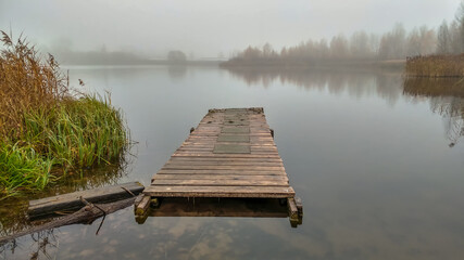 Floating pier on the lake shrouded in fog in autumn