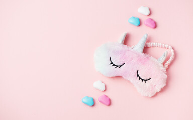 Fluffy fur sleep eye mask unicorn on pink paper background, copy space. Top view, flat lay. Concept relaxation and sweet dreams