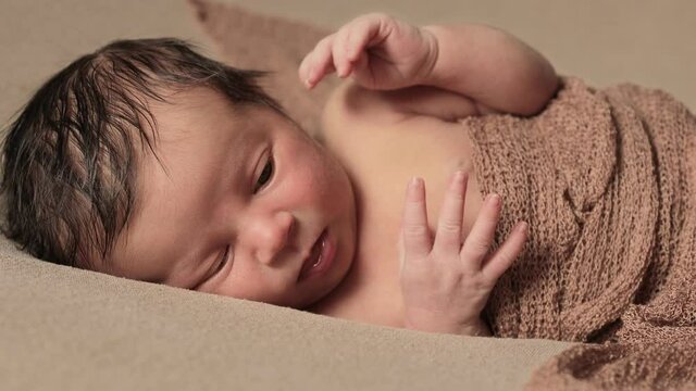 Cute infant girl lying in bed wake up close up. Looking at camera. Childhood. First days of new life