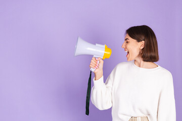 Young brunette in white casual sweater isolated on purple background happy screaming in megaphone copy space point left