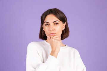 Young brunette in white casual sweater isolated on purple background thinking worried about a question, concerned and nervous