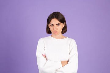 Young brunette in white casual sweater isolated on purple background with gloomy expression needs support and help