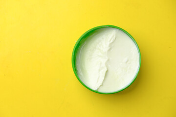 Close up of beauty cream in a container on yellow background 