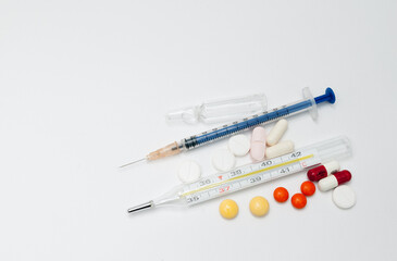 syringe with ampoules and capsules on white background