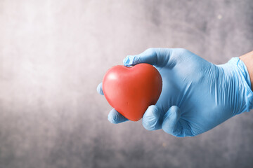  man hand in protective gloves holding red heart on black 