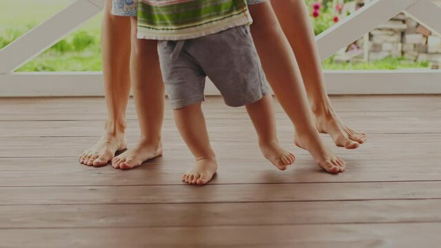 Close view at funny moving of six happy bare feet on wooden terrace on sunny day