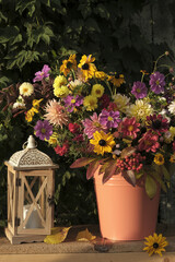 A bouquet of autumn flowers in a bucket, illuminated by the rays of the sun