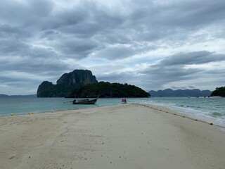 long sandy beach with boat and clear blue sea in thailand