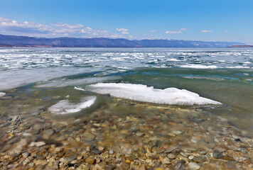 Baikal Lake at spring season. View from Olkhon Island on ice drift in the Small Sea Strait at sunny day. Beautiful landscape with white ice floes melting near the coast. Natural spring background