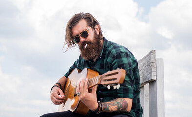 music concept. brutal handsome man with moustache play guitar. mature musician and singer. casual styled guitarist. modern looking bearded hipster with acoustic guitar. Beat droppers