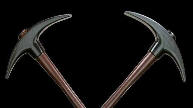 On a black background, two pickaxes as a symbol of the extractive industry are glitters in the rays of light. Macro. Closeup
