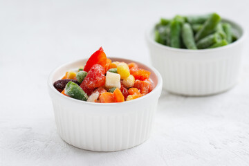 Mix of frozen vegetables in white bowls.