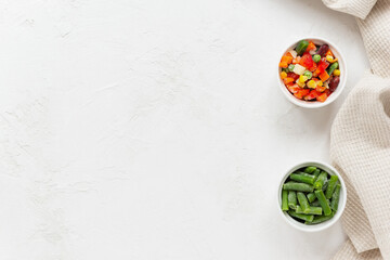 Mix of frozen vegetables in white bowls. Horizontal orientation, copy space, top view.