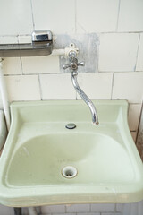 old sink washstand in a bathroom with white tiles.