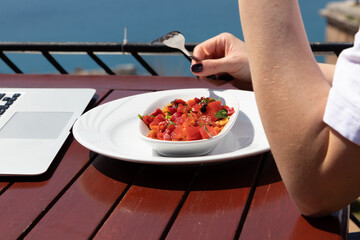 Healthy food concept. Red barbecue pepper in white plate. Young woman eating healthy meal outside in sunny day.