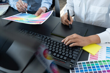 graphic designer team working on web design using color swatches editing artwork using tablet and a...