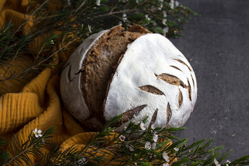 Fresh baked artisan bread on a table. Dark gray background with copy space. Homemade sourdough bread recipe. 