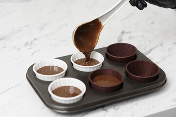 Chocolate cake batter is poured into a mold with beautiful paper cups.