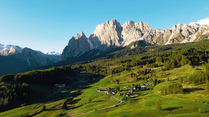 A scenic view of Italian Dolomites near Cortina d'Ampezzo city. Green alpine meadows with snowy mountains in the background