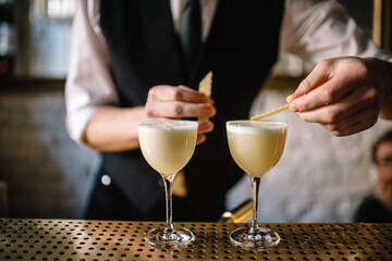 Bartender decorating gin sour cocktail with slices of honeycomb beeswax. 
