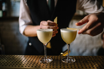 Bartender decorating gin sour cocktail with slices of honeycomb beeswax. 