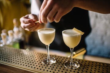 Bartender decorating gin sour cocktail with slices of honeycomb beeswax. 